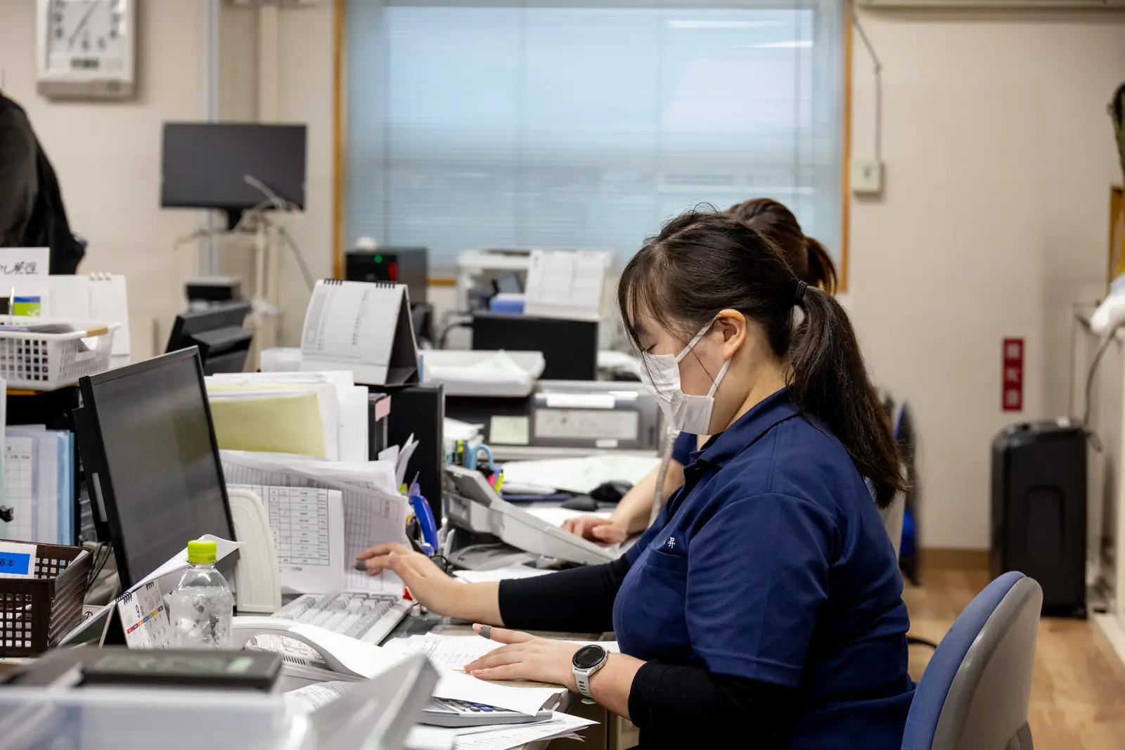Staff member doing office work while checking order details