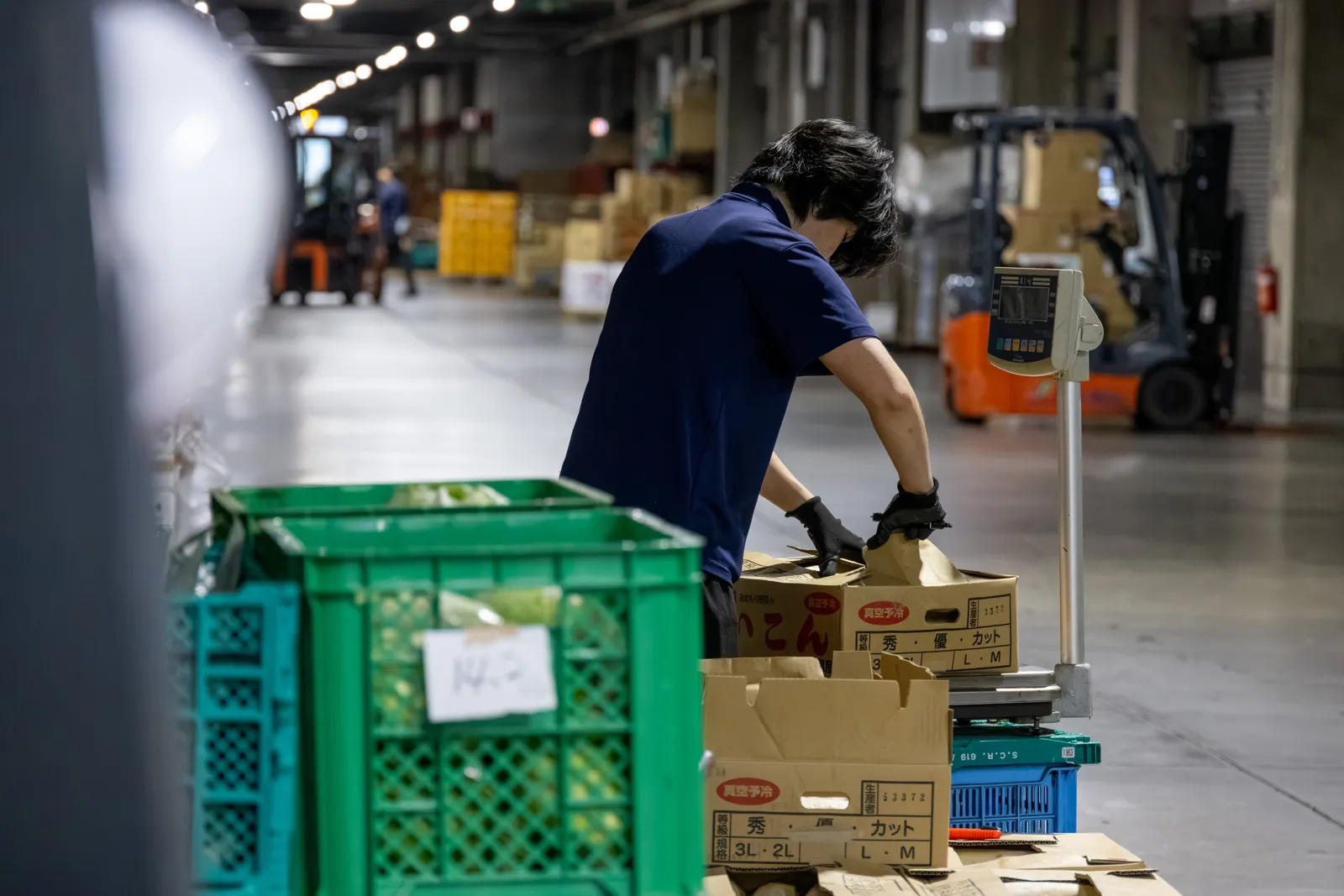 Staff member arranging vegetable containers in an aisle