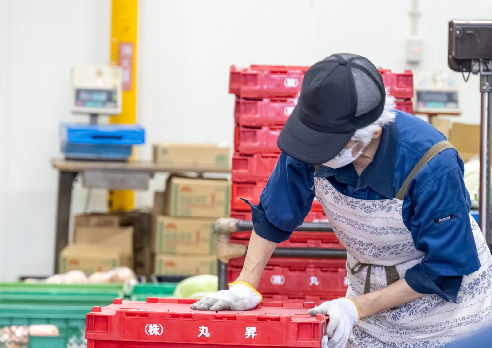 Staff member arranging red "Marusho" containers