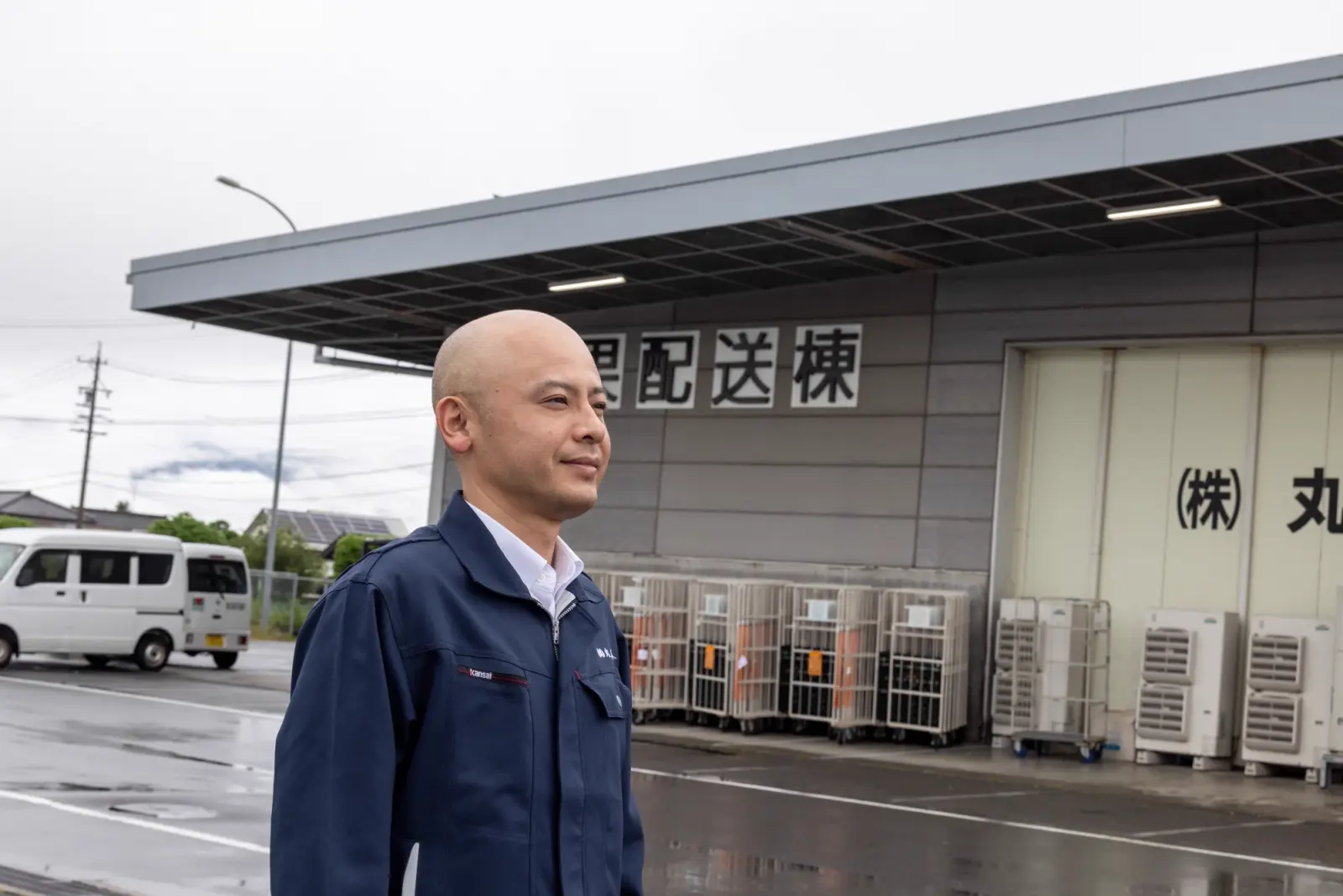 President and Representative Director 中島康喜 gazing into the distance in front of the delivery building